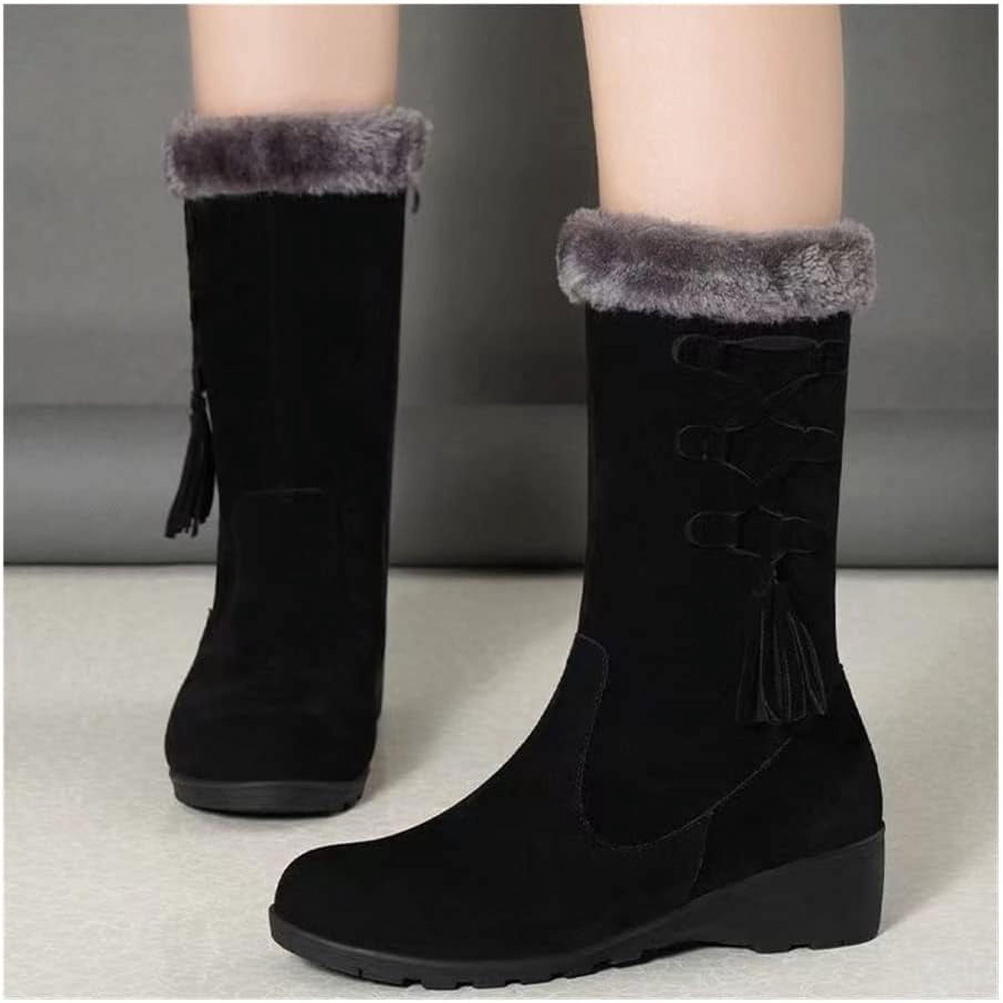 Black suede winter boots with faux fur trim, wedge heel, and tassel detail. Stylish women's footwear for cold weather.