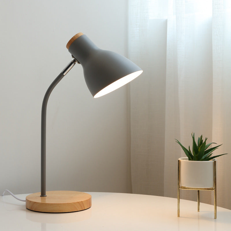 Modern gray desk lamp with wooden base illuminating a white table beside a small potted succulent, ideal for minimalist home office decor.