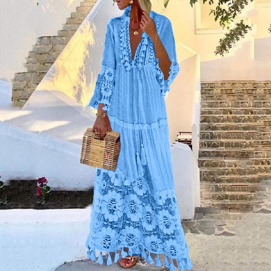 Woman in a blue bohemian lace maxi dress holding a wicker handbag, standing on a sunlit stone staircase. Summer fashion, boho style, vacation outfit.