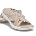 Beige women's slip-on sandals with crisscross straps, cushioned footbed, and white sole. Comfortable summer footwear, casual style, lightweight design.