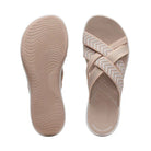 Beige women's slip-on sandals with crisscross straps and textured sole. Comfortable, stylish footwear ideal for casual wear. Perfect summer sandals.