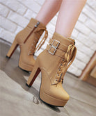 Tan high-heeled ankle boots with lace-up front, double buckle straps, and platform sole on a tiled floor. Fashionable women's footwear.