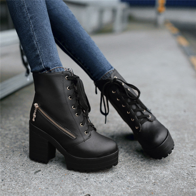 Black leather platform ankle boots with chunky heels, lace-up front, and side zipper detail, worn with blue jeans. Stylish women's footwear.