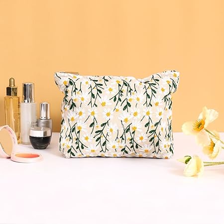 Floral makeup bag with daisy pattern on a white background, surrounded by skincare products and yellow flowers, against a peach backdrop.