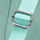 Close-up of a mint green fabric strap with a shiny silver buckle, highlighting durable stitching and modern design. Ideal for backpacks or bags.