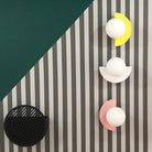 Modern geometric wall decor with striped background, featuring three spherical lights on colorful semi-circular mounts and a black circular element.