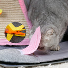 Gray cat playing with interactive felt toy featuring pink ears and a yellow clip, designed for pet enrichment and entertainment.