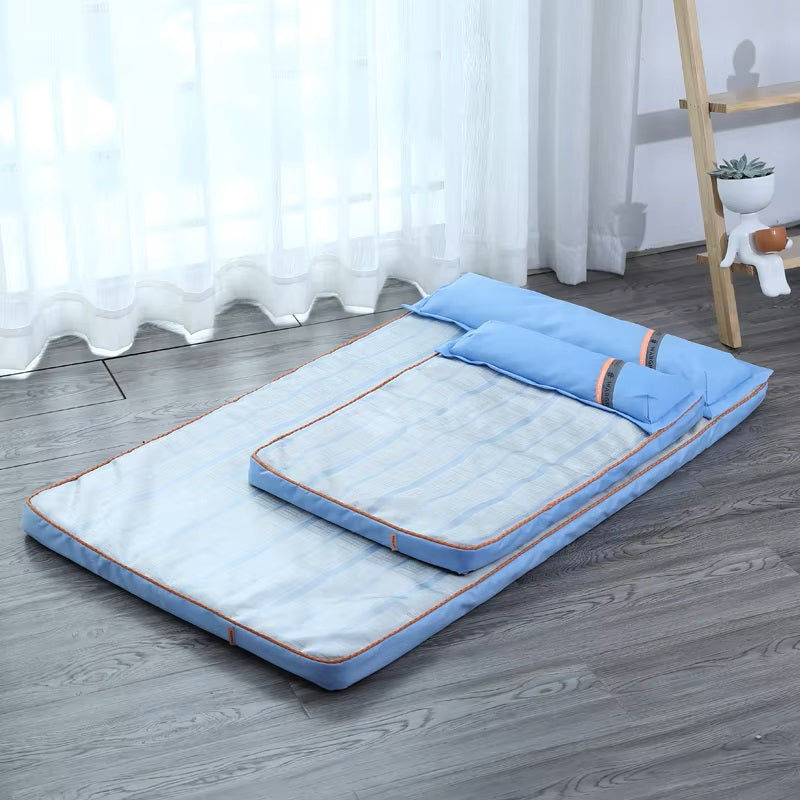 Blue foldable floor mattress with pillow, featuring a striped pattern, placed on wooden flooring near a window. Ideal for compact sleeping solutions.