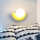 Modern wall lamp with a yellow half-circle design and bright white light, mounted above a bed with black and white patterned pillows.