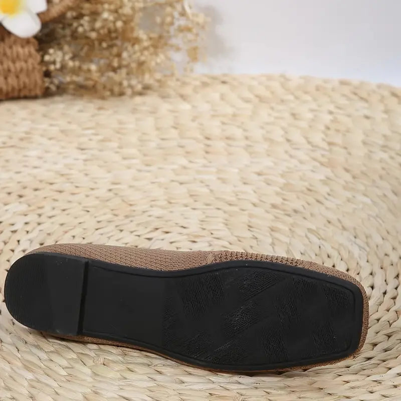 Brown woven espadrille shoe with black rubber sole on a woven mat background, showcasing casual summer footwear design and texture.