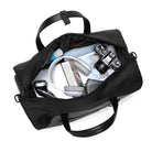 Open black travel duffel bag with camera, headphones, book, and toiletries. Perfect for travel, gym, or weekend trips. Durable and spacious design.