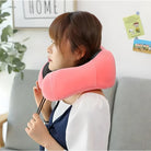 Woman using a pink travel neck pillow with adjustable strap, sitting on a couch. Ideal for comfort and support during travel. Cozy home setting.