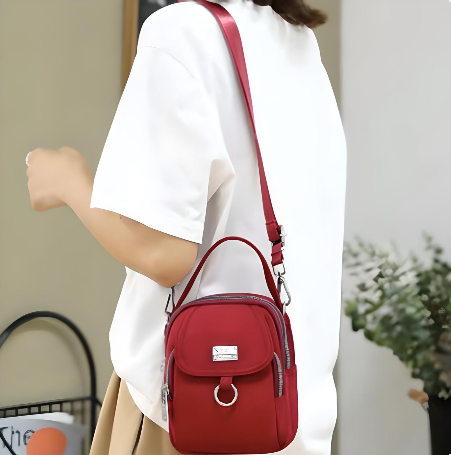 Woman wearing a white shirt and beige skirt, carrying a stylish red crossbody bag with a top handle and silver accents, perfect for casual outings.