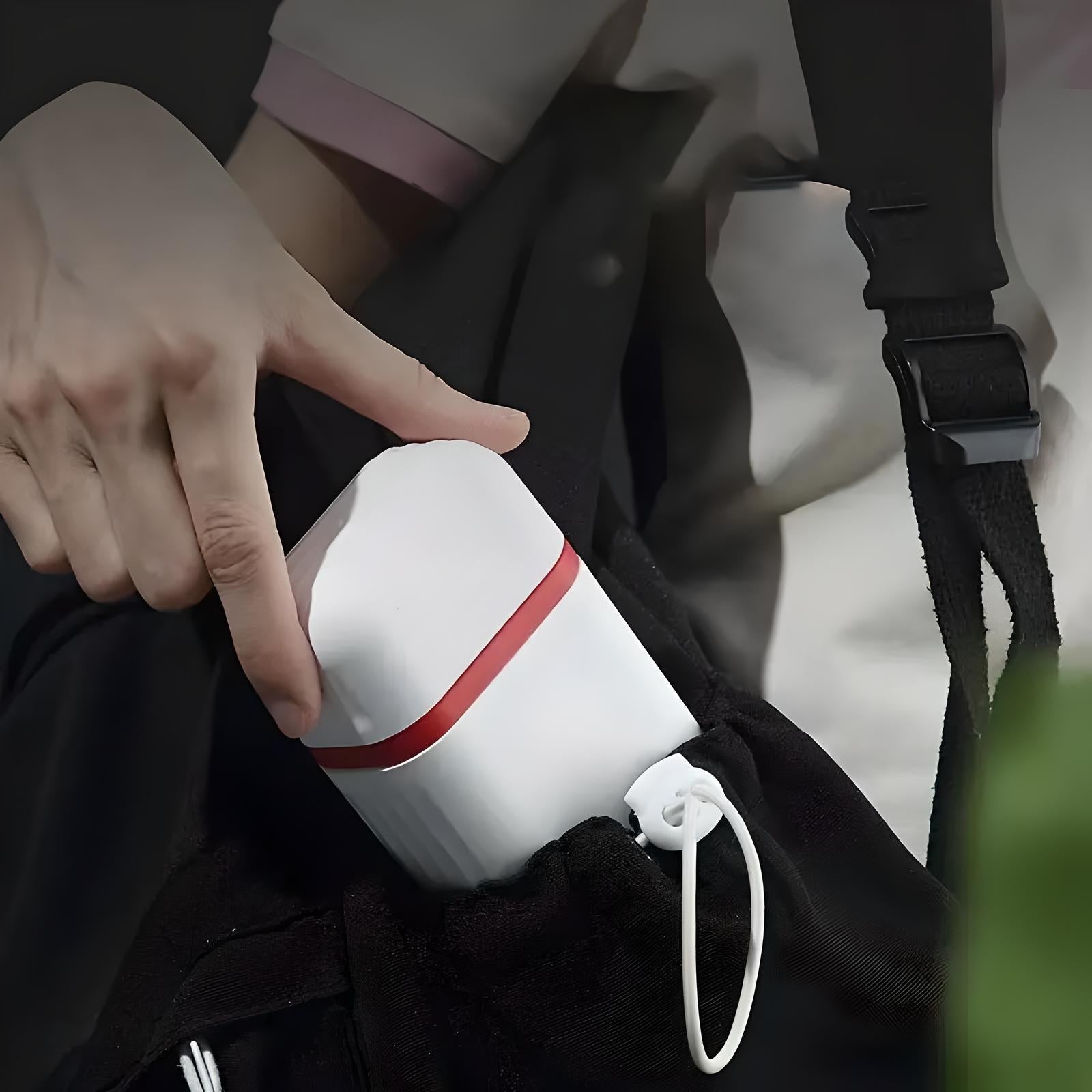 Person placing a portable white and red mini projector into a black bag, highlighting compact design and convenience for travel and presentations.