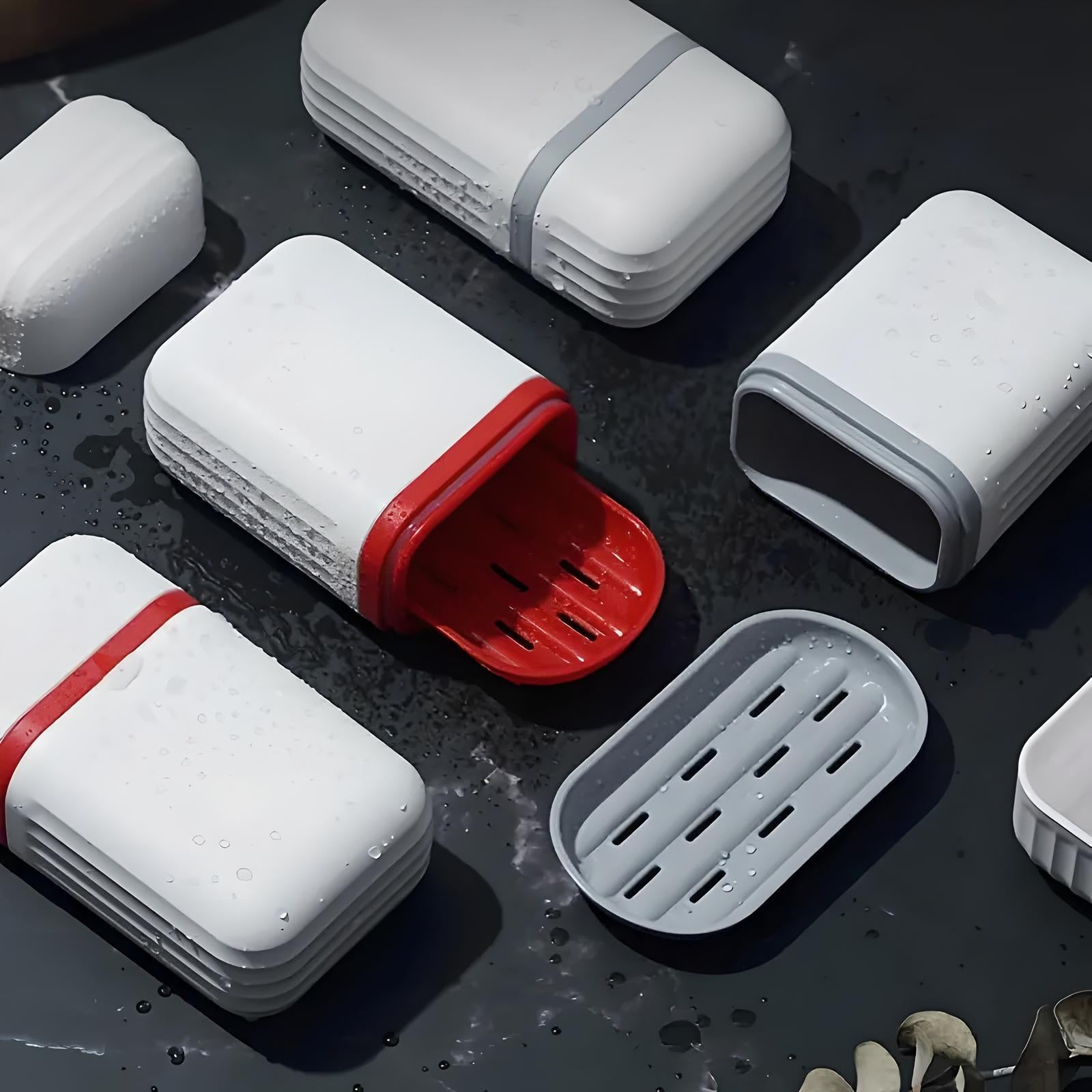 White and red soap dishes with drainage slots on a dark wet surface, featuring modern design and water-resistant material. Ideal for bathroom organization.