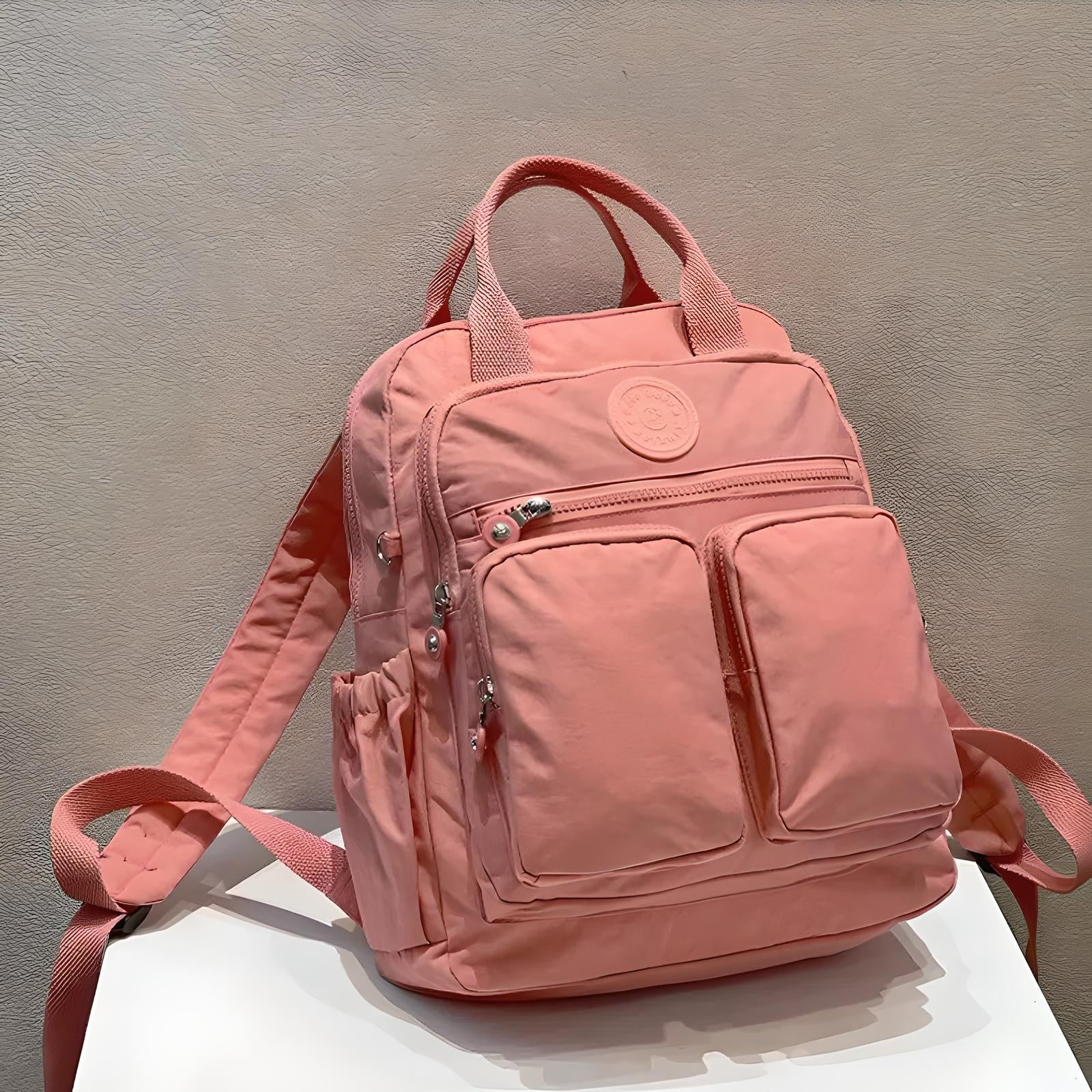 Pink backpack with multiple pockets, durable zippers, and adjustable straps on a white surface. Ideal for school, travel, or everyday use.