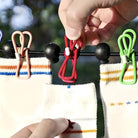 Hands clipping colorful socks on a clothesline with red, green, and pink clothespins. Outdoor laundry drying, eco-friendly, sustainable living.