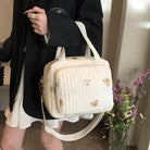 Stylish quilted beige handbag with bear print, adjustable strap, and zipper closure, held by a person in a black jacket. Fashion accessory.