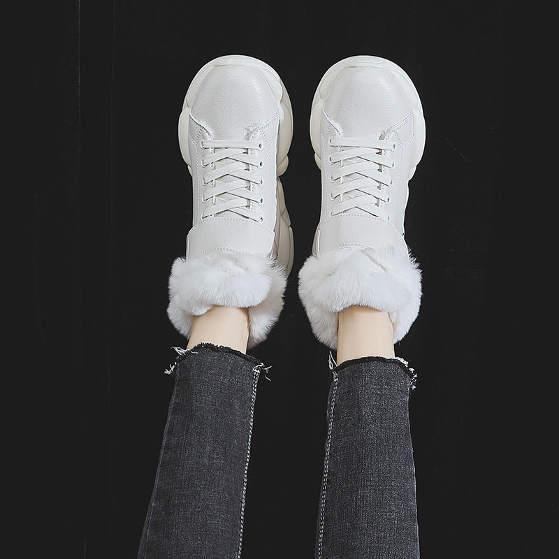 White fur-lined sneakers on black background, worn with frayed black jeans. Fashionable winter footwear, cozy and stylish design.