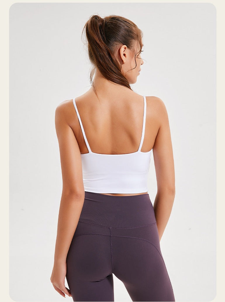 Woman in white sports bra and purple leggings, viewed from the back, showcasing activewear fashion. Ideal for yoga, gym, or fitness activities.