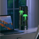 LED jellyfish lamp on desk beside laptop, glowing green in dark room. Modern home decor, ambient lighting, unique aquarium-style night light.