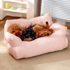 Small dog in a cozy pink pet bed, wearing a blue outfit, relaxing indoors. Perfect for pet comfort, luxury dog beds, and stylish pet accessories.