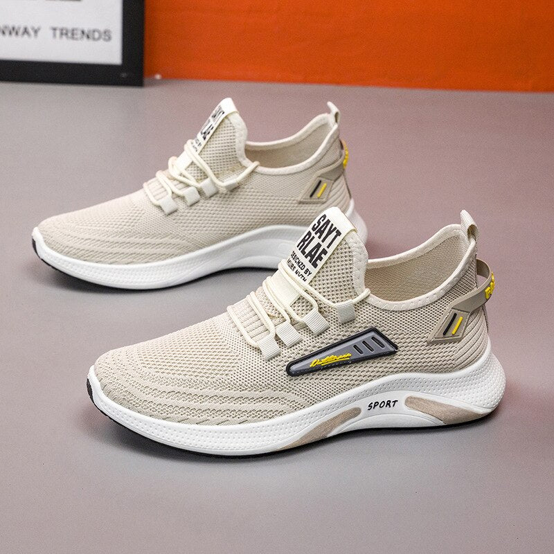 Beige athletic sneakers with breathable mesh design, cushioned sole, and "Stay Real" text, ideal for running and casual wear.