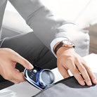 Man using a blue fabric shaver on a garment, wearing a gray suit and a brown leather watch. Lint remover, clothing care, grooming tool.