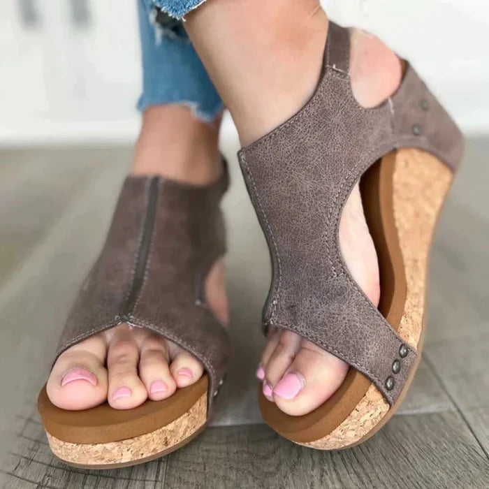 Women's brown leather wedge sandals with cork sole, open toe design, and rivet details. Perfect for casual summer fashion and comfort.