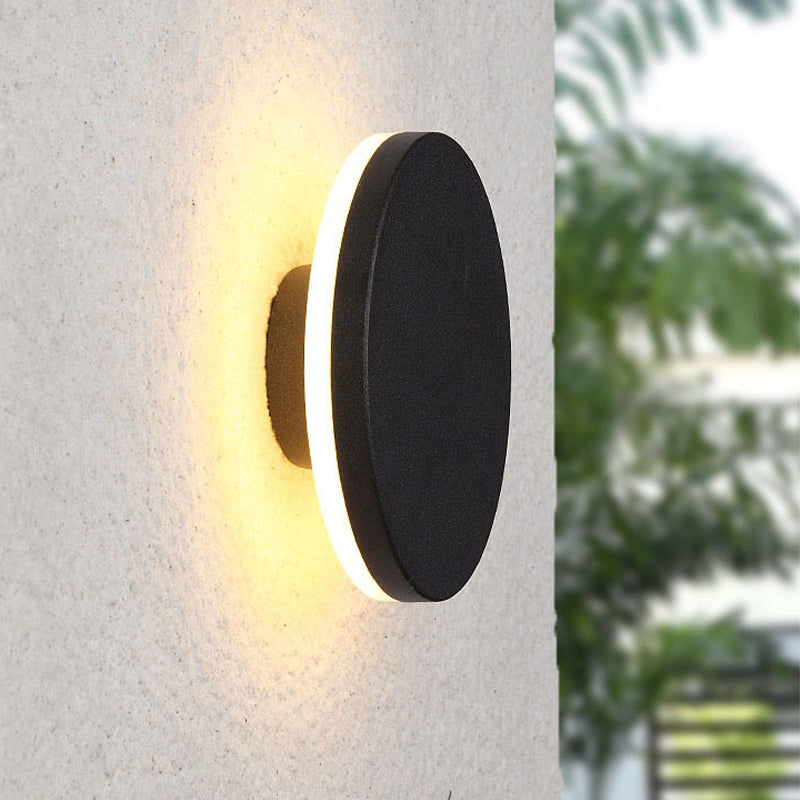 Modern black LED wall sconce with warm white light, mounted on a textured beige wall, ideal for outdoor lighting and contemporary home decor.