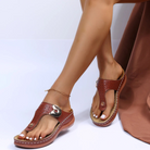 Women's brown leather sandals with gold buckle detail, featuring a comfortable wedge sole. Perfect for summer fashion and casual wear.