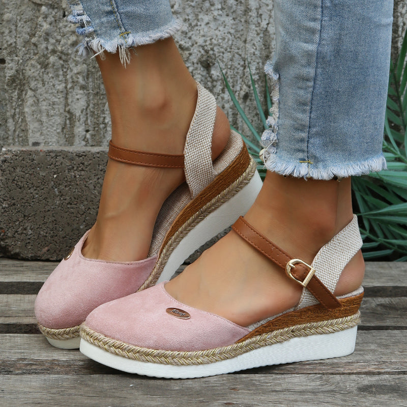 Women's pink espadrille sandals with ankle strap, jute platform, and white sole. Casual summer footwear paired with distressed denim jeans.