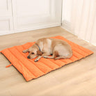 Orange waterproof foldable dog mat, durable outdoor pet bed, travel-friendly, on wooden floor.