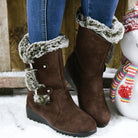 Brown faux fur-lined winter boots with buckle detail, worn with blue jeans, on a snowy surface. Stylish women's footwear for cold weather.