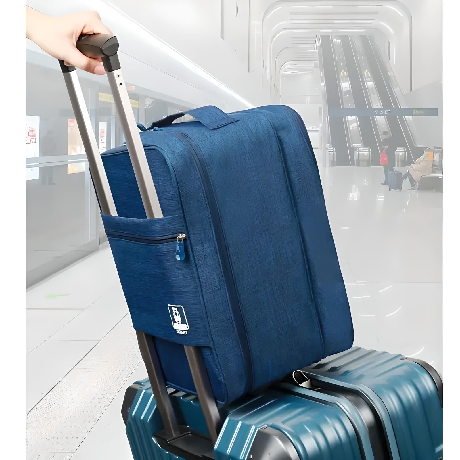 Blue carry-on luggage with telescopic handle on top of a larger suitcase in a modern airport terminal with escalators in the background.