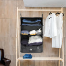 Hanging travel organizer with multiple compartments, packed with clothes, next to a white dress on a wooden rack. Ideal for efficient packing and storage.