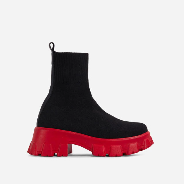 Black sock boot with chunky red platform sole, mid-calf height, stretch fabric, thick heel, Chelsea style. Women's autumn winter fashion footwear.