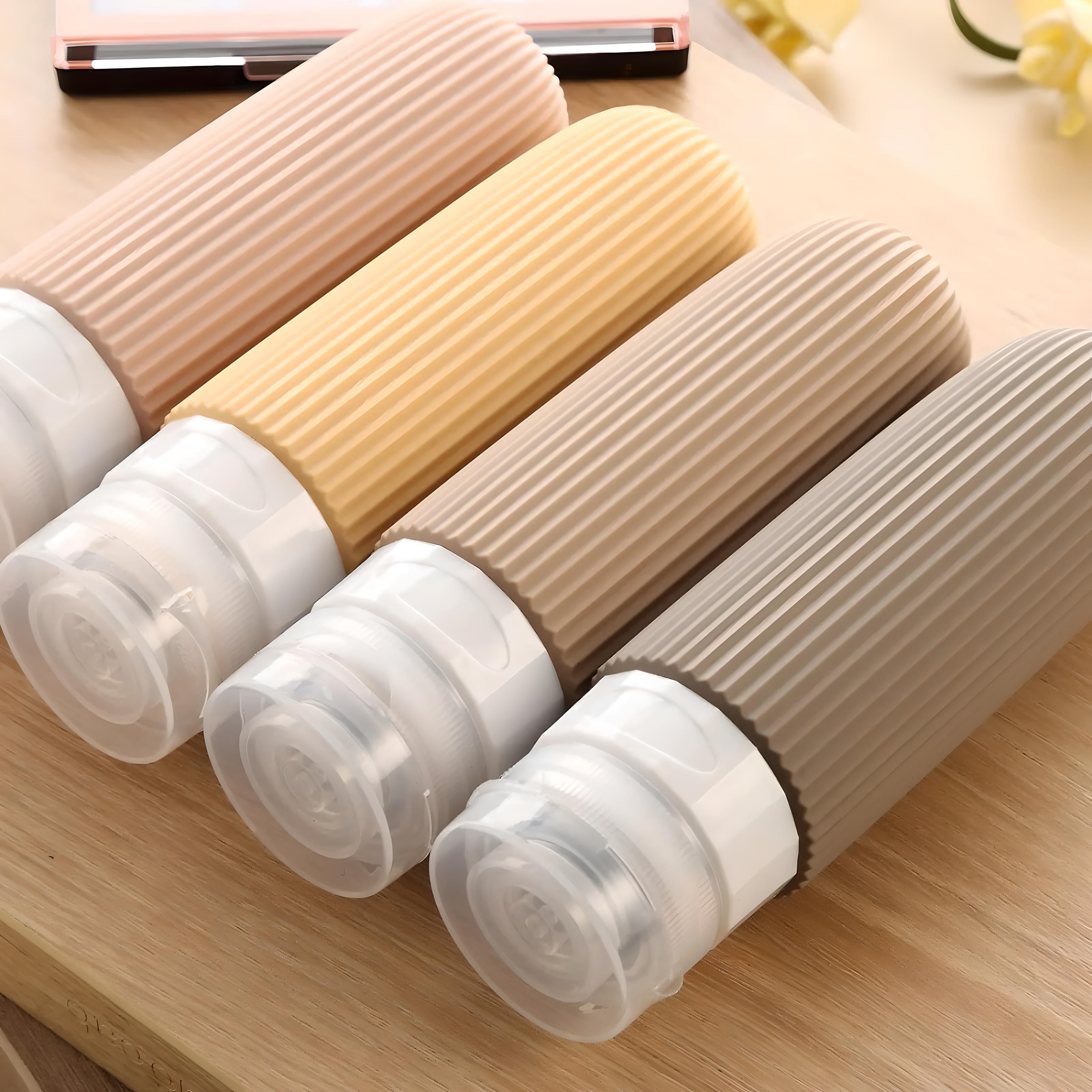 Set of four silicone travel bottles with ribbed design, ideal for toiletries. Leak-proof, TSA-approved containers in neutral colors on a wooden surface.