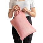 Woman holding a pink plush pillow with removable cover, wearing a white shirt and plaid pants. Cozy home decor, soft cushion, interior design accessory.