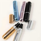 Assorted travel perfume atomizers in metallic colors: gold, silver, blue, pink, and black. Portable refillable spray bottles for fragrance.