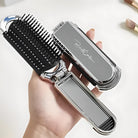 Compact foldable hairbrush with mirror, featuring a sleek silver design and black bristles, ideal for travel and on-the-go grooming.