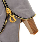 Gray suede ankle boot with gold zipper detail and stacked heel, featuring a decorative gold charm. Fashionable women's footwear.