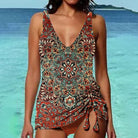 Woman wearing a bohemian paisley print swimsuit with a tie-side design, standing by the ocean. Summer beachwear, boho swimwear fashion.