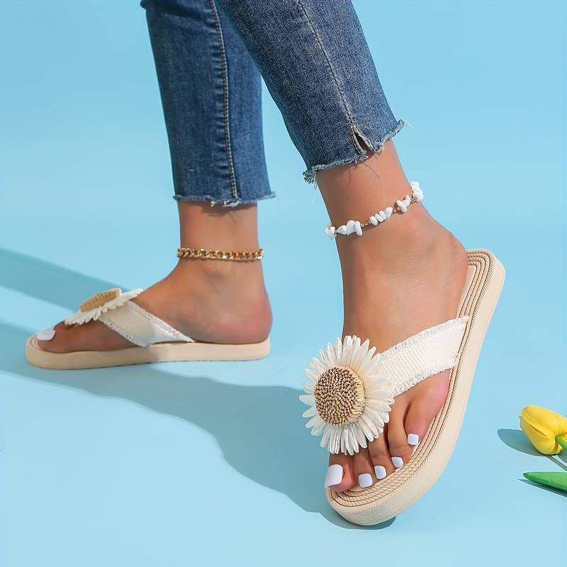 Woman wearing stylish daisy flower sandals with denim jeans on a blue background. Summer fashion footwear, casual chic style, floral sandals.