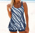 Woman wearing a navy blue and white striped tankini swimsuit on a beach, showcasing summer swimwear fashion.