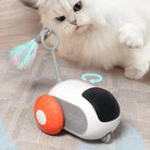 Interactive cat toy with colorful feather and wheels, engaging white Persian cat on wooden floor. Perfect for pet playtime and exercise.