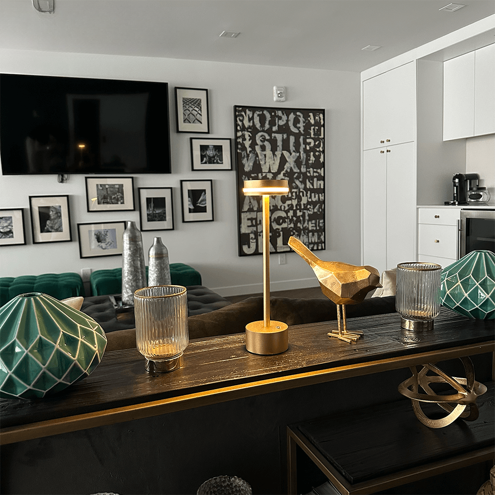 Modern living room with stylish decor, featuring a gold bird sculpture, geometric teal vases, and a sleek table lamp on a wooden console.