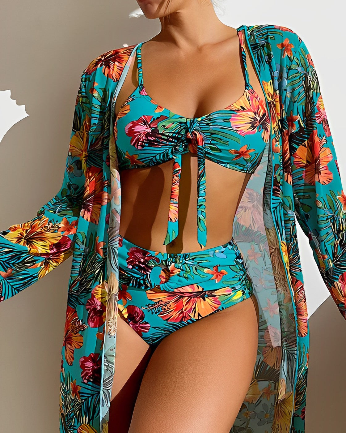 Woman wearing a vibrant floral bikini set with matching cover-up, featuring tropical patterns in blue, orange, and green. Summer beachwear fashion.