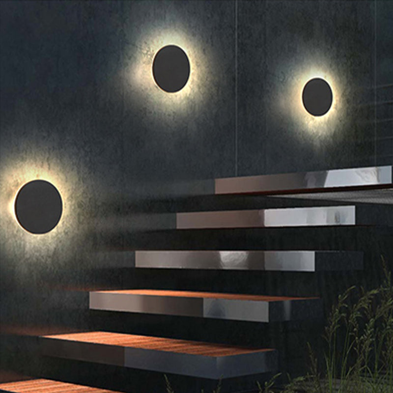 Modern staircase with sleek black steps illuminated by circular wall lights, creating a contemporary ambiance. Perfect for interior design inspiration.