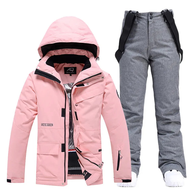 Pink women's ski jacket with hood and gray ski pants, waterproof winter sportswear set.